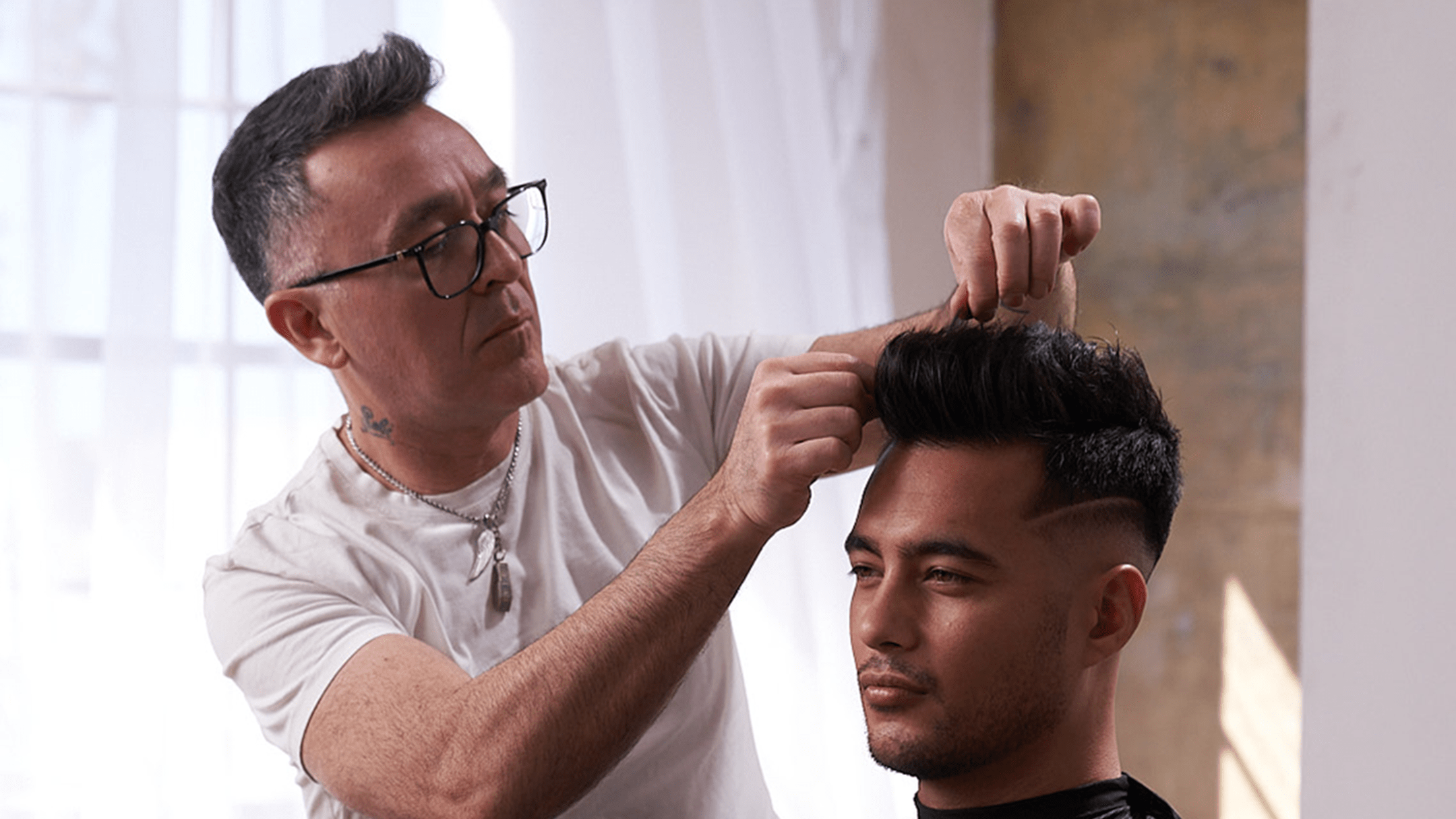 Barber with glasses and white t-shirt styling hair