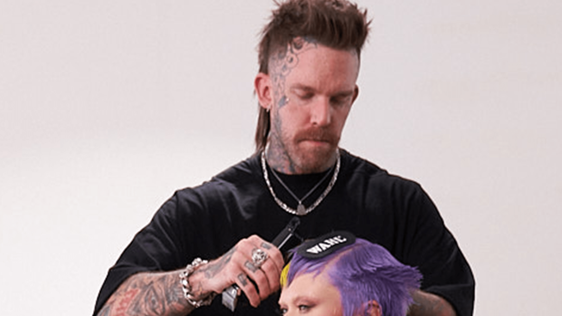 Barber with face tattoos and mohawk styling hair