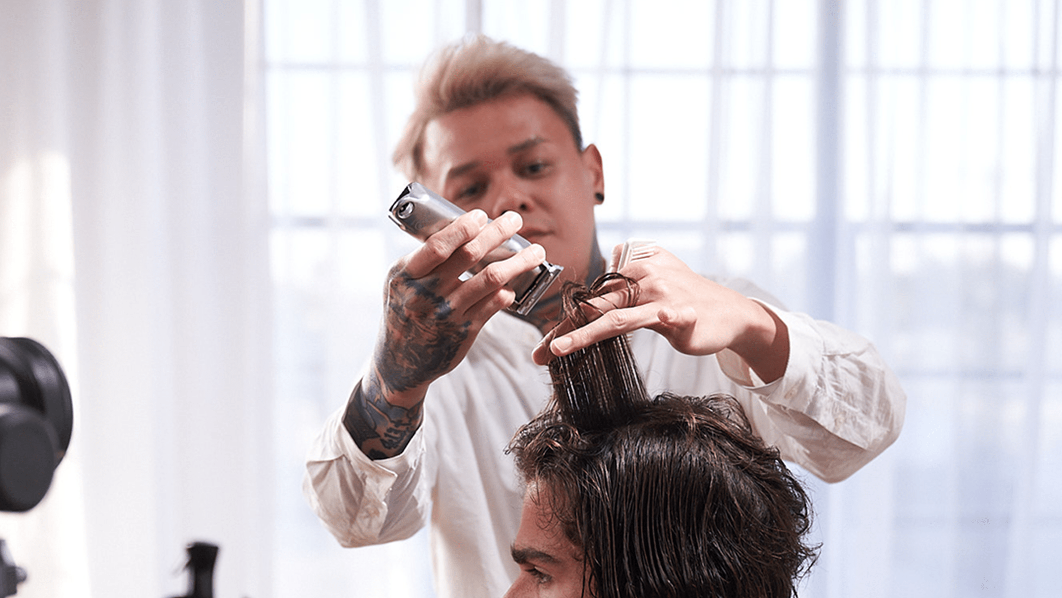 Barber with short blond and white shirt styling hair