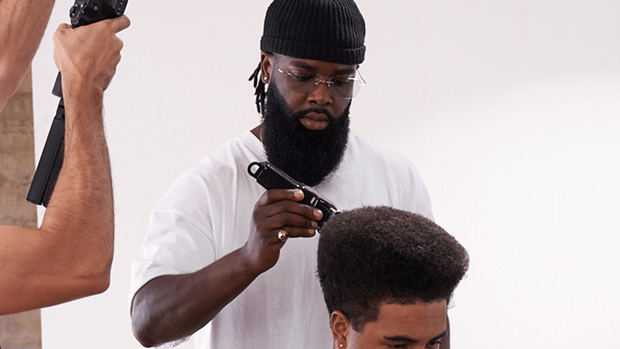 Barber with long black beard and white shirt styling hair