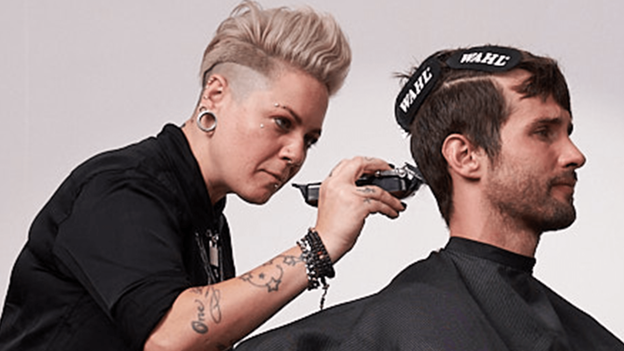 Barber with short blond hair and black shirt styling hair