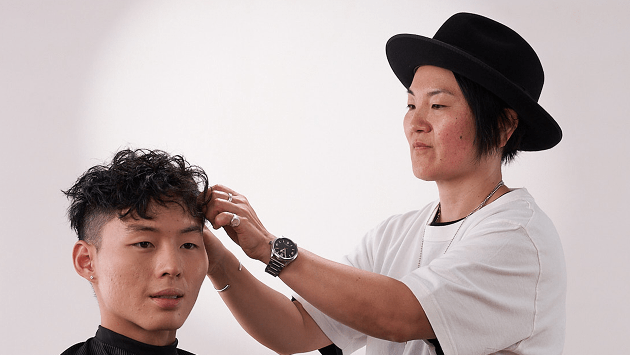 Barber with black hair and white shirt styling hair