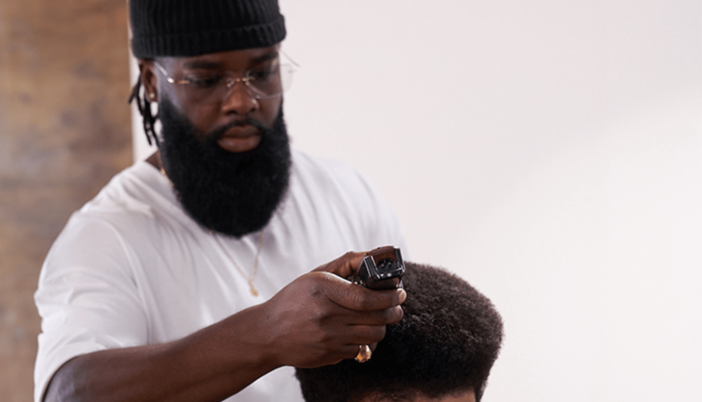 Barber wearing a black hat and a t-shirt styling hair